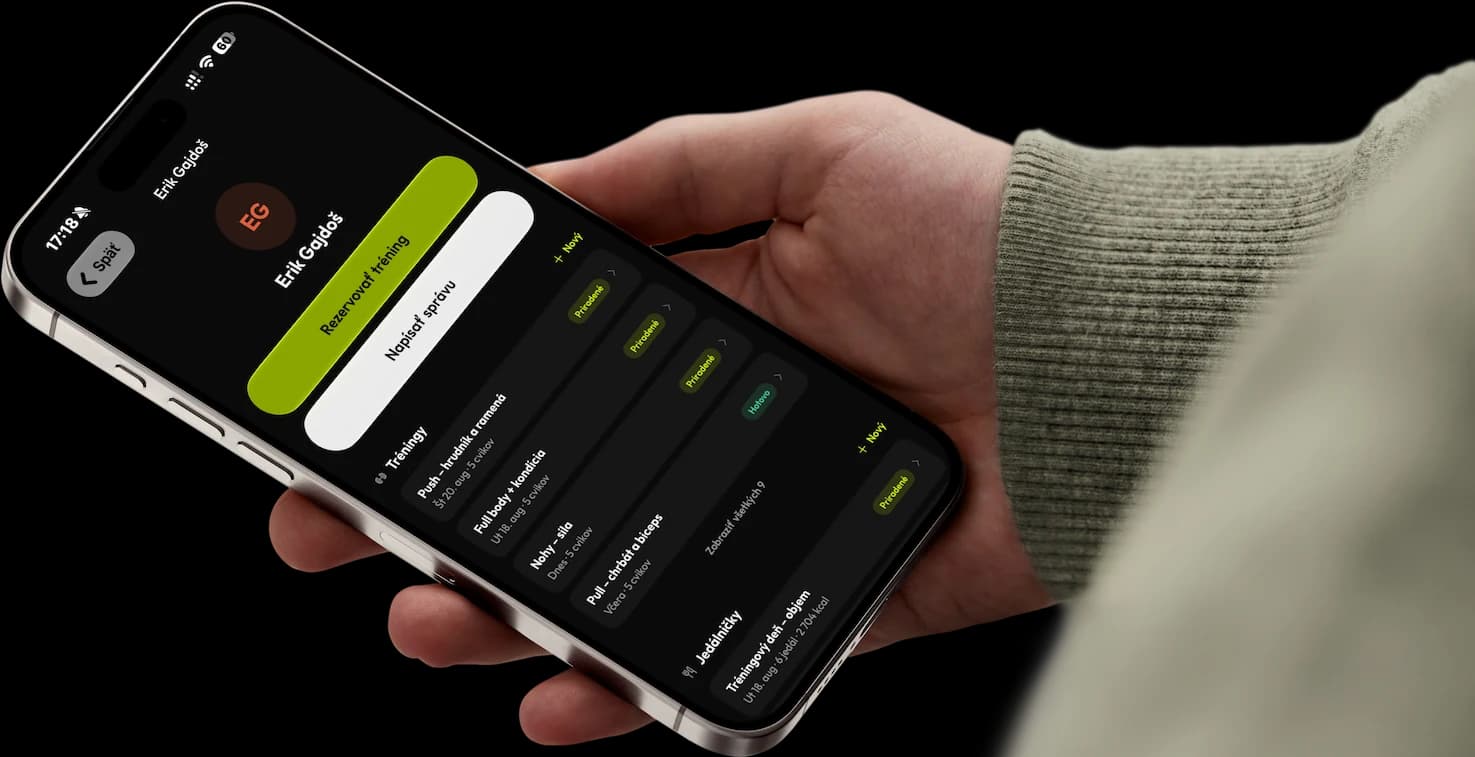 Trenér drží telefon s aplikací RepUp Trainer — karta klienta s tréninky a jídelníčky